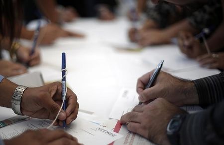 © Reuters. People fill up job applications during a job fair in San Jose