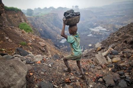 © Reuters. A boy carries coal at an open cast coal field at Dhanbad district in Jharkhand
