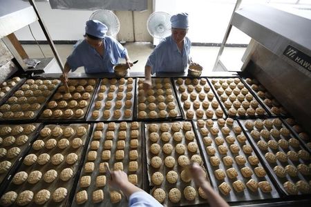 © Reuters. Freshly-baked mooncakes pass along a conveyor belt at a mooncakes factory in Shanghai