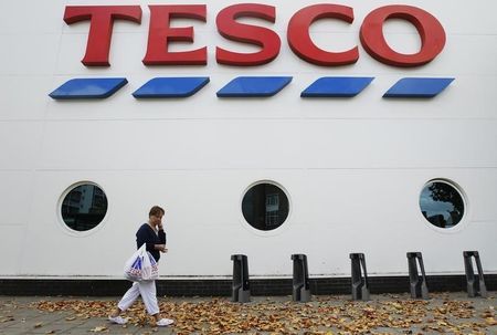 © Reuters. A shopper passes a Tesco supermarket in London