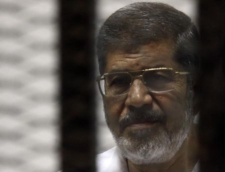 © Reuters. Ousted Egyptian president Mohamed Mursi stands behind bars during his trial at a court in Cairo