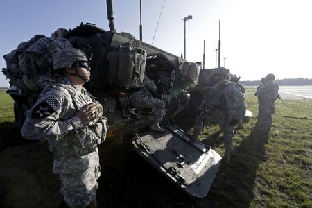 © Reuters. U.S. soldiers stand near an armoured personal carrier during the "Steadfast Javelin II" military exercise in Lielvarde