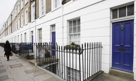 © Reuters. A woman walks past houses on a street in London