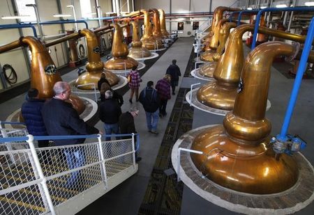 © Reuters. Visitors look at copper whisky stills during a tour of the Glenfiddich whisky distillery in Dufftown, Scotland