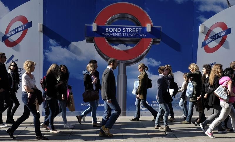 &copy; Reuters People walk past signs for a London Underground improvement programme on Oxford Street in London