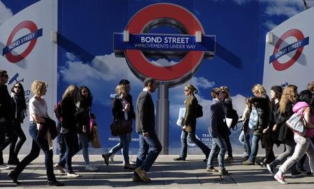 © Reuters. People walk past signs for a London Underground improvement programme on Oxford Street in London
