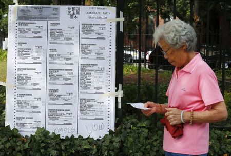 © Reuters. A woman arriving at a polling station walks past an enlarged copy of the democratic primary ballot in primary election day in Boston