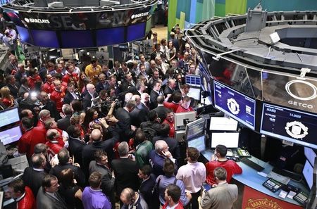 © Reuters. People gather at the post for the start of trading of Manchester United Ltd at the NY Stock Exchange