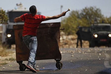 © Reuters. A Palestinian man throws a stone towards Israeli troops during clashes following the funeral of Issa al Qitri in Ramallah