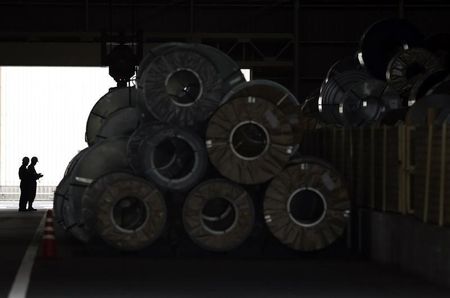 © Reuters. Workers control a crane to move a steel coil inside a factory in Tokyo