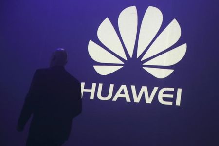 © Reuters. A man walks past a logo during the presentation the Huawei's new smartphone, the Ascend P7, launched by China's Huawei Technologies in Paris
