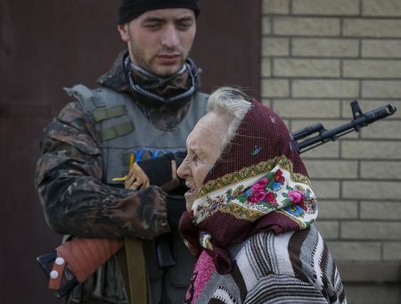 © Reuters. Una donna ucraina passa davanti ad un soldato a Volnovakha