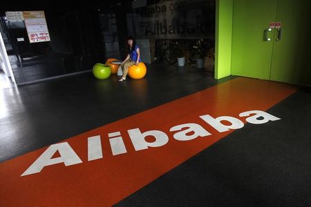 © Reuters. An employee sits next to a logo of Alibaba during a media tour organised by government officials at the company's headquarters on the outskirts of Hangzhou