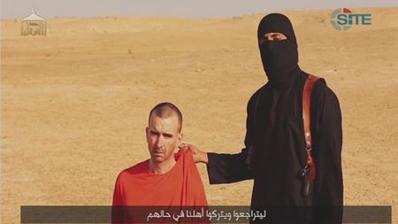 © Reuters. A video purportedly showing threats being made to a man Islamic State named as David Haines by a masked IS fighter in an unknown location in this still image from video released by Islamic State