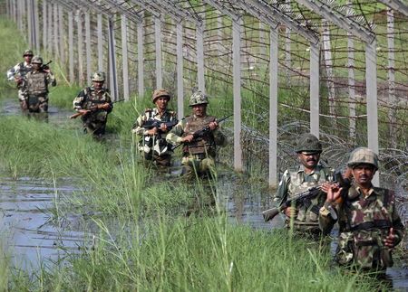 © Reuters. Indian BSF soldiers patrol the fenced border with Pakistan as they wade through the flood waters on the outskirts of Jammu