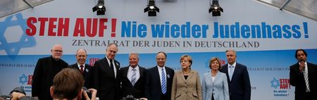 © Reuters. German Chancellor Merkel and speakers pose on stage after anti-Semitism demo in Berlin