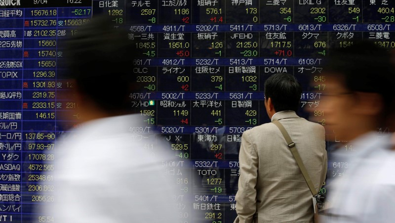 &copy; Reuters A man looks at an electronic stock quotation board outside a brokerage in Tokyo