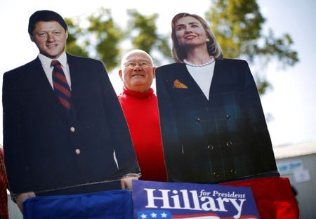 © Reuters. Supporter Dick Furinash holds up cardboard cut-outs of former U.S. Secretary of State Hillary Clinton and her husband former U.S. President Bill Clinton at the 37th Harkin Steak Fry in Indianola
