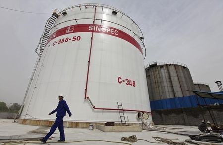 © Reuters. An employee walks past oil tanks at a Sinopec refinery in Wuhan, Hubei province