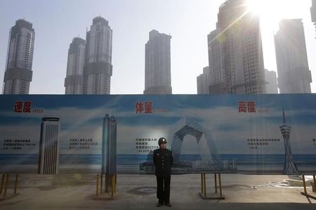 © Reuters. A security guard stands next to an advertising board in front of a residential compound under construction in Wuhan