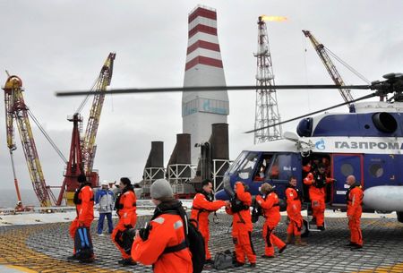 © Reuters. Journalists disembark from a helicopter upon their arrival at the Prirazlomnoye oil platform located in the Pechora Sea