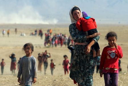 © Reuters. Displaced people from the minority Yazidi sect, fleeing violence from forces loyal to the Islamic State in Sinjar town, walk towards the Syrian border