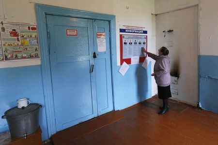 © Reuters. A woman looks at a list of candidates before voting in regional governors election at a polling station in the village of Verkhnaya Biryusa