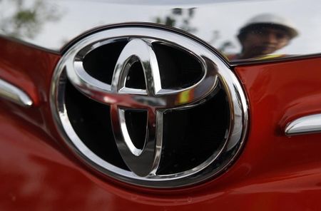 © Reuters. Worker is reflected next to the emblem of a Toyota Vios sedan at a stockyard of the Toyota Philippines manufacturing plant in Sta Rosa, Laguna, south of Manila