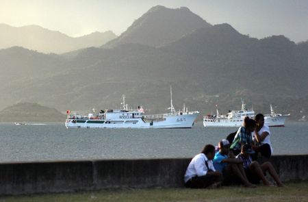 © Reuters. Locals sit on a wall situated on the foreshore of the harbour in the Fiji capital of Suva