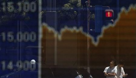 © Reuters. Man looks up as he is reflected on an electronic board displaying Japan's Nikkei average outside a brokerage in Tokyo