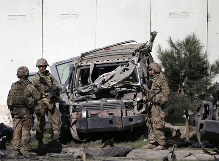 © Reuters. U.S. troops keep watch near a damaged vehicle at the site of suicide attack in Kabul