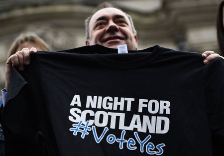 © Reuters. Scotland's First Minister Alex Salmond  holds a t-shirt promoting a concert being held in support of a 