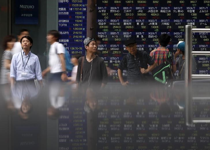 &copy; Reuters Pedestrians standing in front of an electronic board showing the various stock prices outside a brokerage are reflected in a polished stone surface, in Tokyo