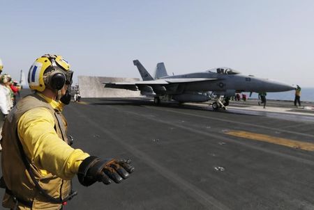 © Reuters. Flight deck crew member confirms the deck is all clear before a F/A-18C Hornet take offs USS George H.W. Bush in the Gulf