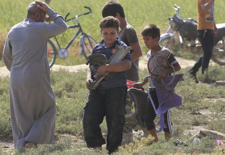 © Reuters. Children carry a remnant of a war plane that crashed on the outskirts of Raqqa in northeast Syria