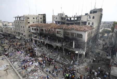 © Reuters. Palestinians gather around the remains of a commercial center, which witnesses said was hit by an Israeli air strike, in Rafah