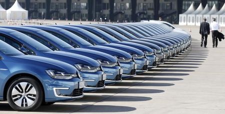 © Reuters. People pass row of Volkswagen e-Golf cars during company's annual news conference in Berlin