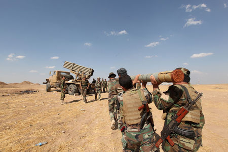 © Reuters. Iraqi Kurdish Peshmerga troops load rockets into a launcher during fighting with Islamic State militants in Khazir