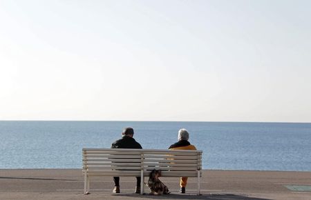 © Reuters. Elderly people sit on a bench to take in the sun along the Promenade Des Anglais in Nice