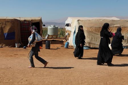 © Reuters. Syrian Refugees walk inside an informal settlement in Deir al-Ahmar, Bekaa valley