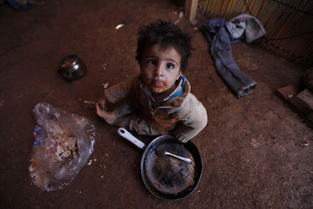 © Reuters. A Syrian refugee child eats inside his family's tent at an informal settlement in Deir al-Ahmar, Bekaa valley