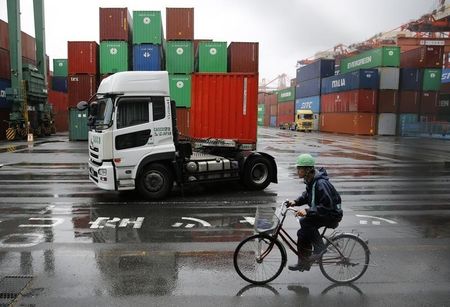 © Reuters. A worker rides a bicycle in a container area at a port in Tokyo