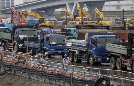 © Reuters. A man stands next to tracks as he controls the traffic at a construction site in Tokyo