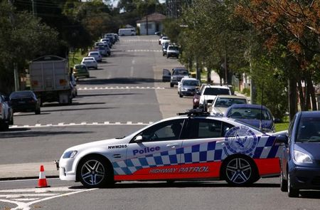 © Reuters. A policeman sits in his patrol car as part of a road block on the street where a house was involved in pre-dawn raids in the western Sydney suburb of Guilford