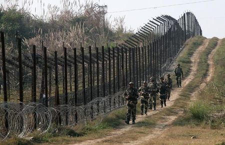 © Reuters. Indian BSF soldiers patrol the fenced border with Pakistan at Babiya village