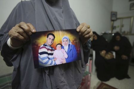 © Reuters. Mother of Palestinian Assouli holds a picture of him with his wife and daughter at her house in Khan Younis in the southern Gaza Strip