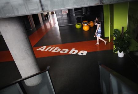 © Reuters. Un empleado pasa sobre un logo de Alibaba en sus oficinas en Hangzhou