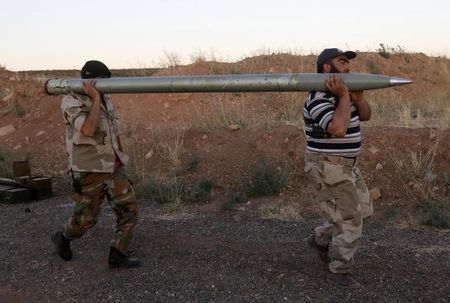 © Reuters. Free Syrian Army fighters carry a rocket before firing it towards Hama military airport that is controlled by forces loyal to Syria's President Assad, in the Hama countryside