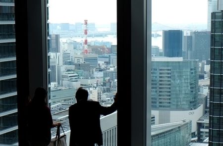 © Reuters. A man and a woman watch outside at the lobby of an office building in Tokyo