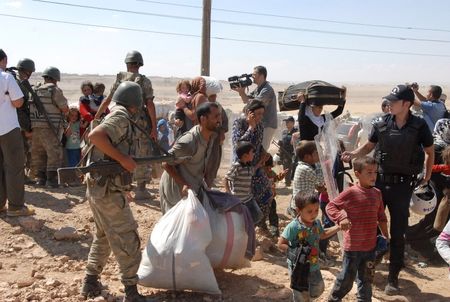 © Reuters. Syrian Kurds cross the border fence into Turkey near the southeastern town of Suruc in Sanliurfa province